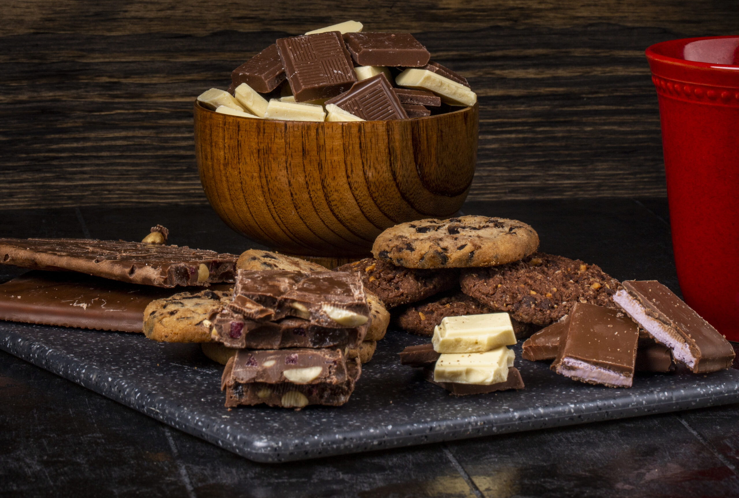 side view of dark and white chocolate in a wooden bowl and oatmeal cookies scattered on dark background Manjar pie de limón 230 grs